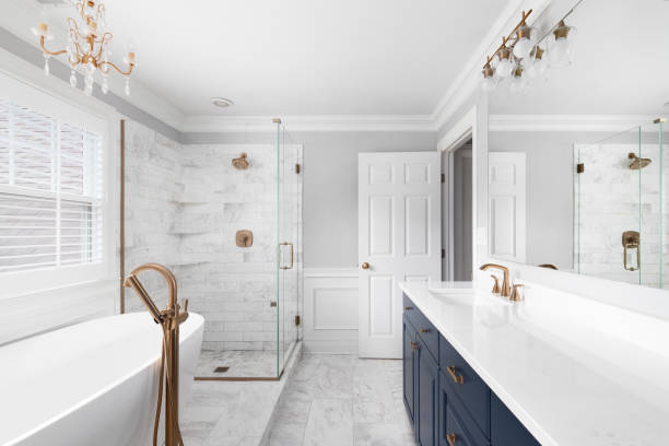 A beautiful bathroom with a blue vanity cabinet, standalone bathtub and shower, and gold faucets. bathroom remodeling Lee County TX