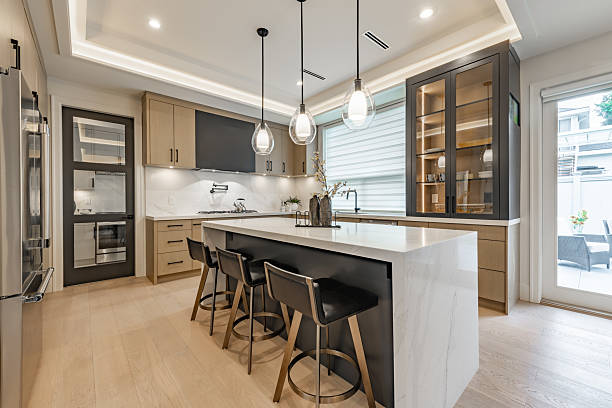Kitchen interior with bar stools white countertops wooden cabinets pendant lighting extra kitchen sink glass cabinets hardwood floors stainless steel appliances window with coverings blinds drawn. kitchen remodeling Steiner Ranch